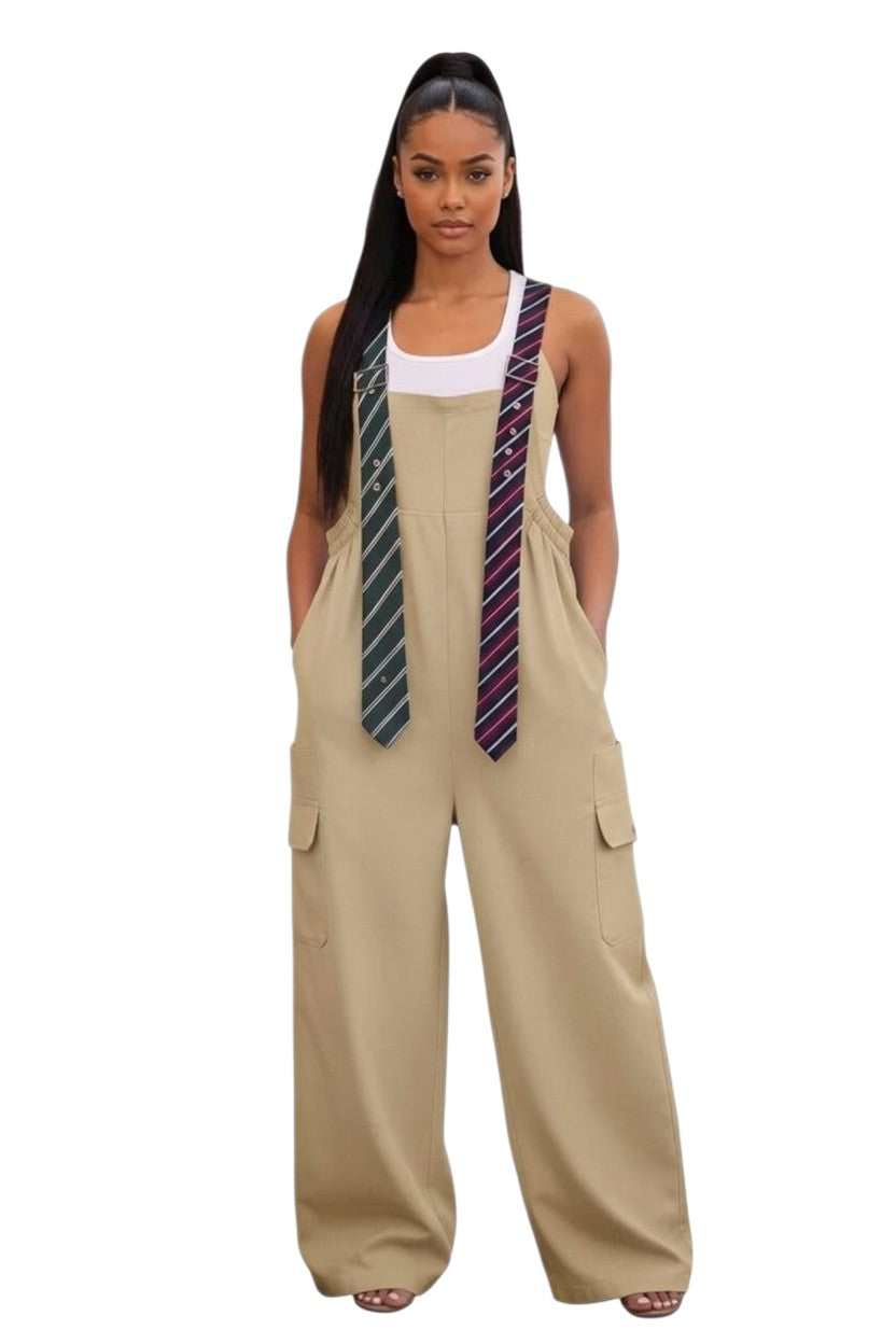 Model wearing a Hush Boutique beige oversized jumpsuit with cargo pockets and decorative striped tie straps.