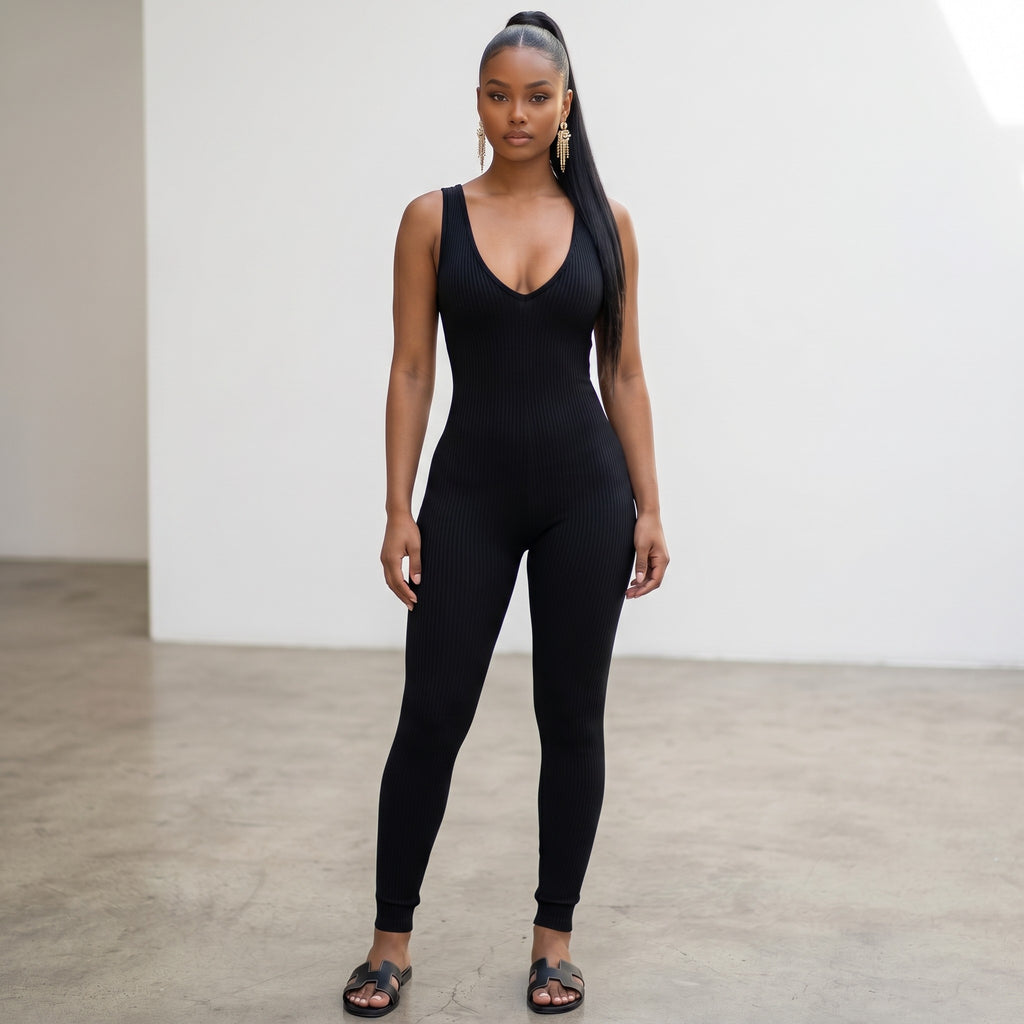 Model wearing a black Hush Boutique ribbed sleeveless jumpsuit with a deep V-neckline in a minimalist studio setting.