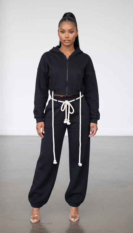 Hush Boutique black two-piece set featuring a cropped zip-up hoodie and wide-leg sweatpants with rope waist ties.