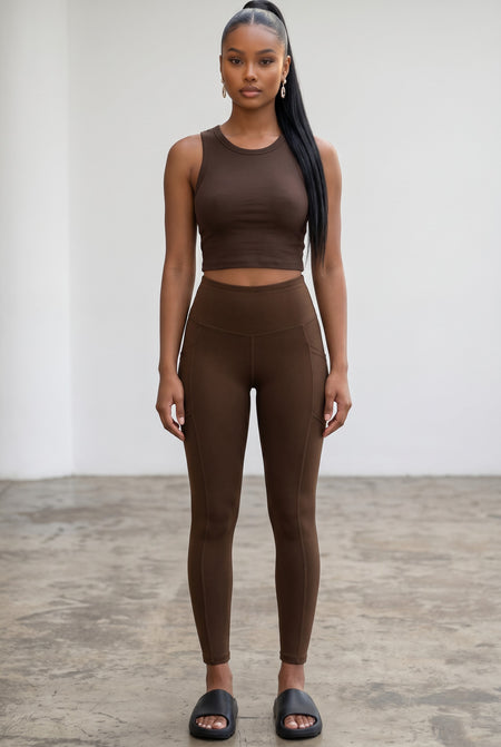 Hush Boutique dark brown buttery soft full-length leggings with side pockets worn by a model in a studio.