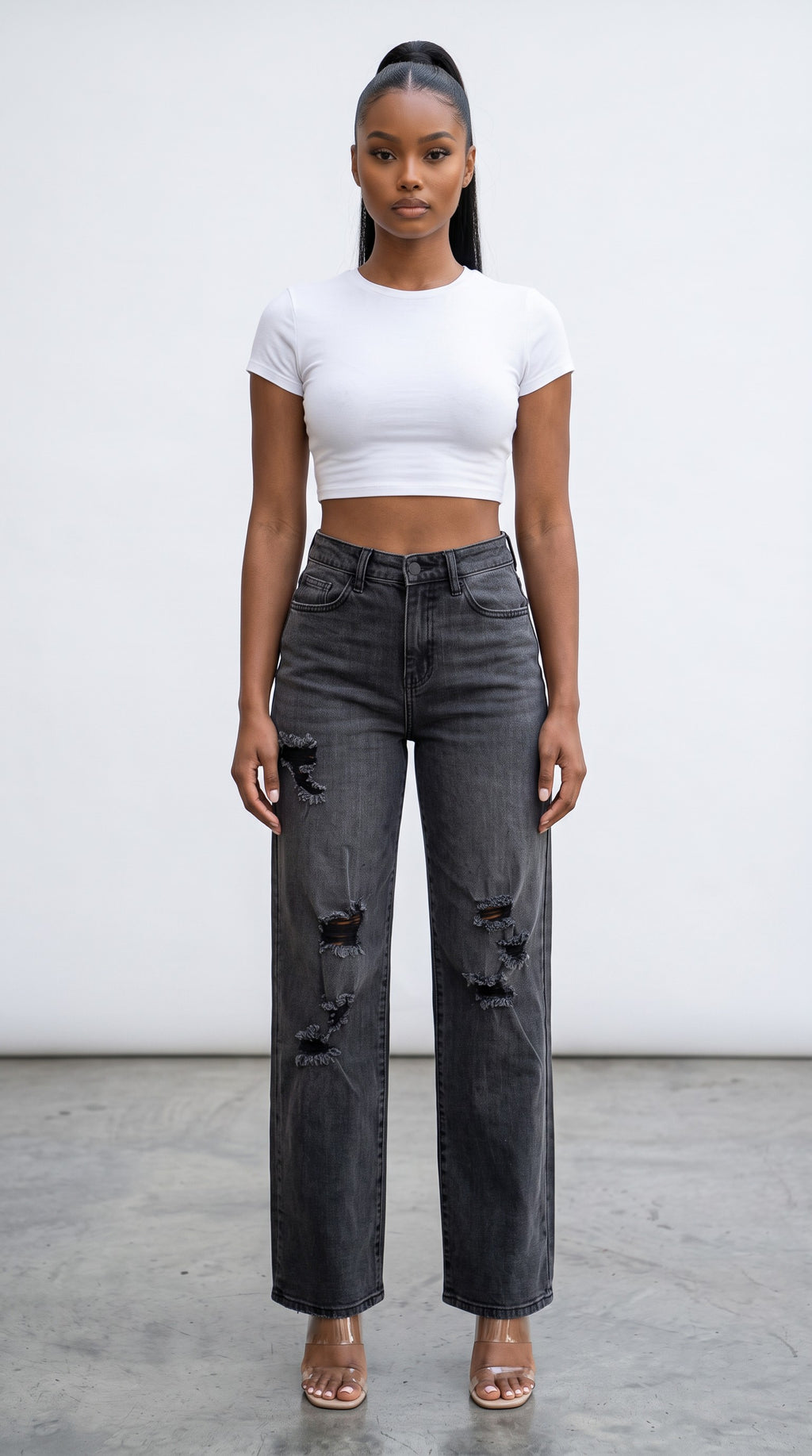 Model wearing Hush Boutique high-rise distressed black wide-leg jeans with a white crop top