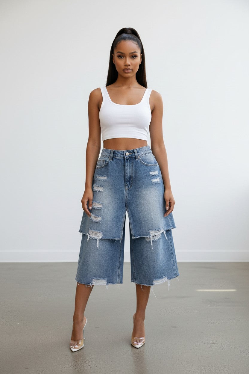 Model wearing Hush Boutique double layer distressed blue denim Bermuda shorts with a white tank top