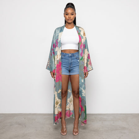 Hush Boutique maxi kimono with oversized floral print in blue, pink, and green, worn over a white tank and denim shorts