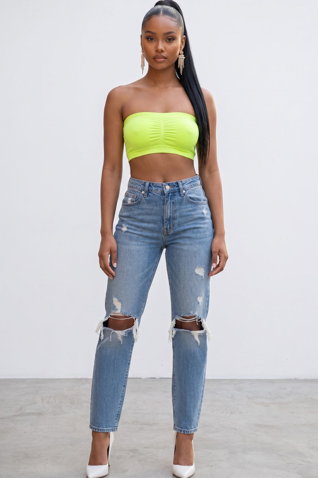 Model wearing a neon yellow Hush Boutique seamless strapless bandeau top with padded cups and distressed blue jeans.