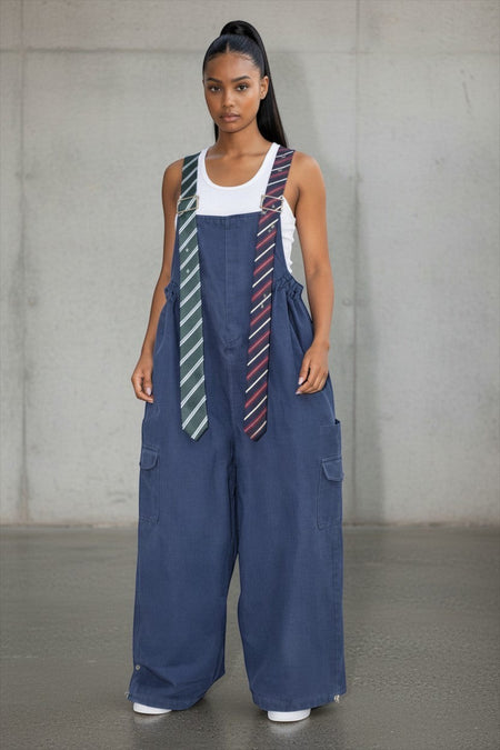 Hush Boutique oversized blue denim jumpsuit with unique tie-style shoulder straps and cargo pockets on a model
