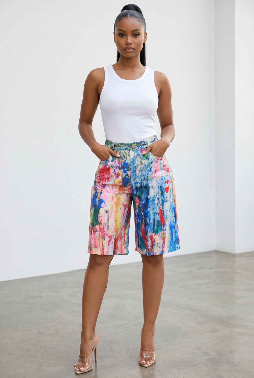 Model wearing Hush Boutique painted graphic straight shorts with a white tank top and clear high heels