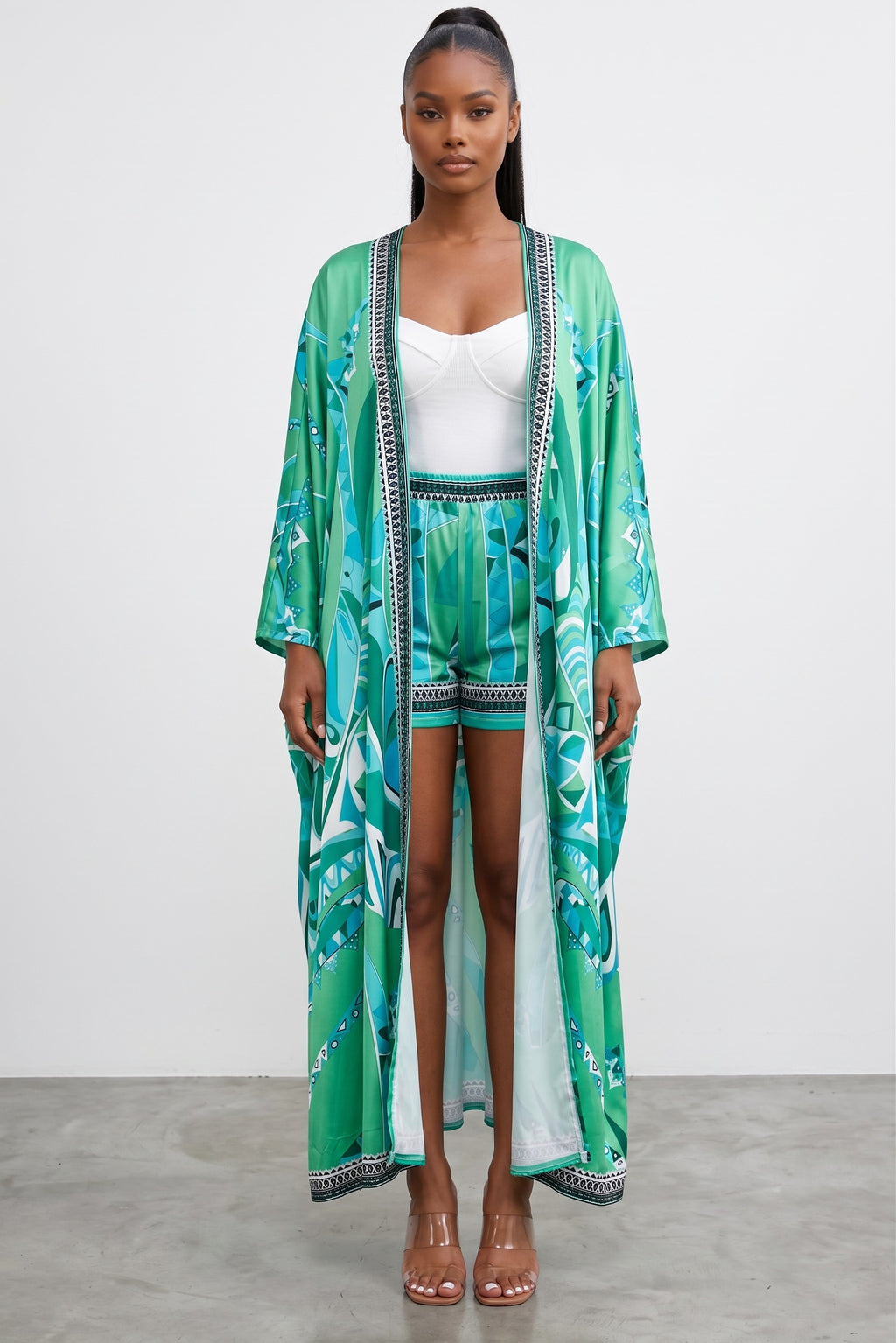 Model wearing Hush Boutique green and turquoise printed two-piece set with a flowy maxi cardigan and pull-on shorts.