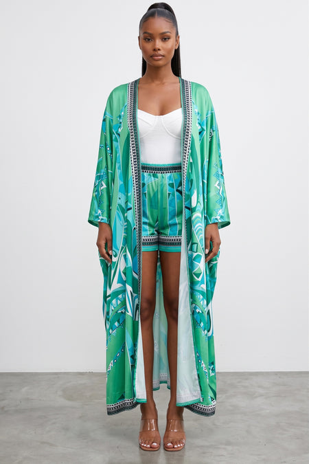 Model wearing Hush Boutique green and turquoise printed two-piece set with a flowy maxi cardigan and pull-on shorts.