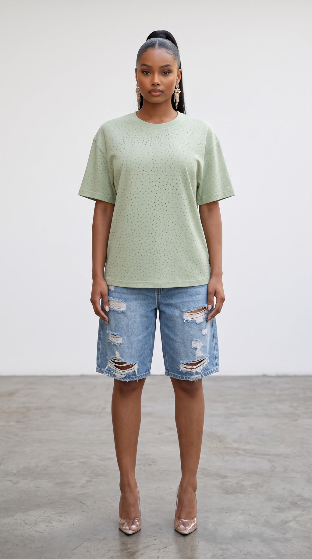 Model wearing a sage green Hush Boutique oversized t-shirt with delicate rhinestone stud detailing and distressed denim shorts
