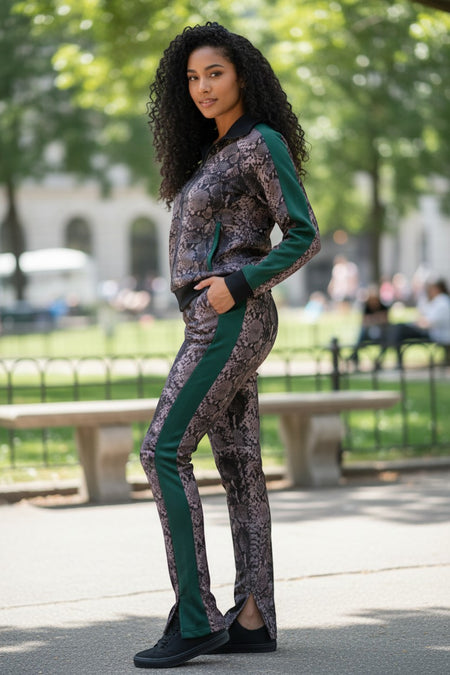 Hush Boutique women's two-piece tracksuit with a snake print pattern, black collar, and green side stripes. Features a zip-up jacket and split-hem pants.